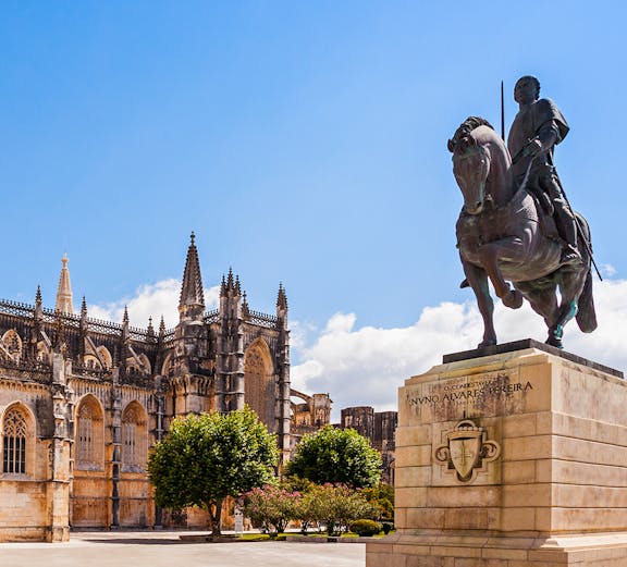 Equestrian statue near Batalha Monastery, Portugal, with Gothic architecture in the background.