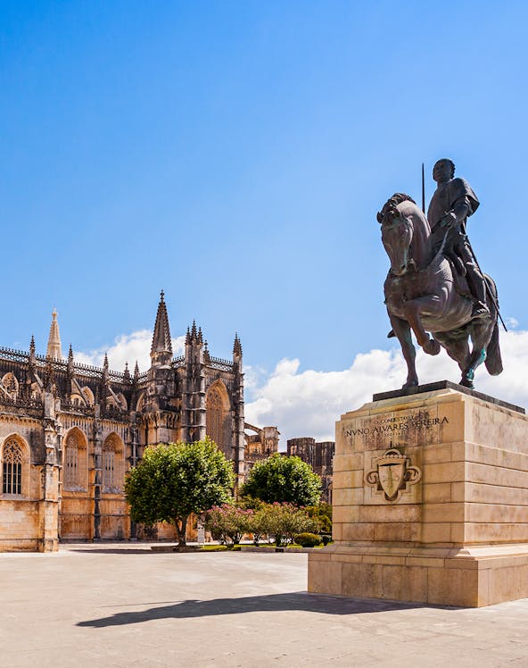 Equestrian statue near Batalha Monastery, Portugal, with Gothic architecture in the background.