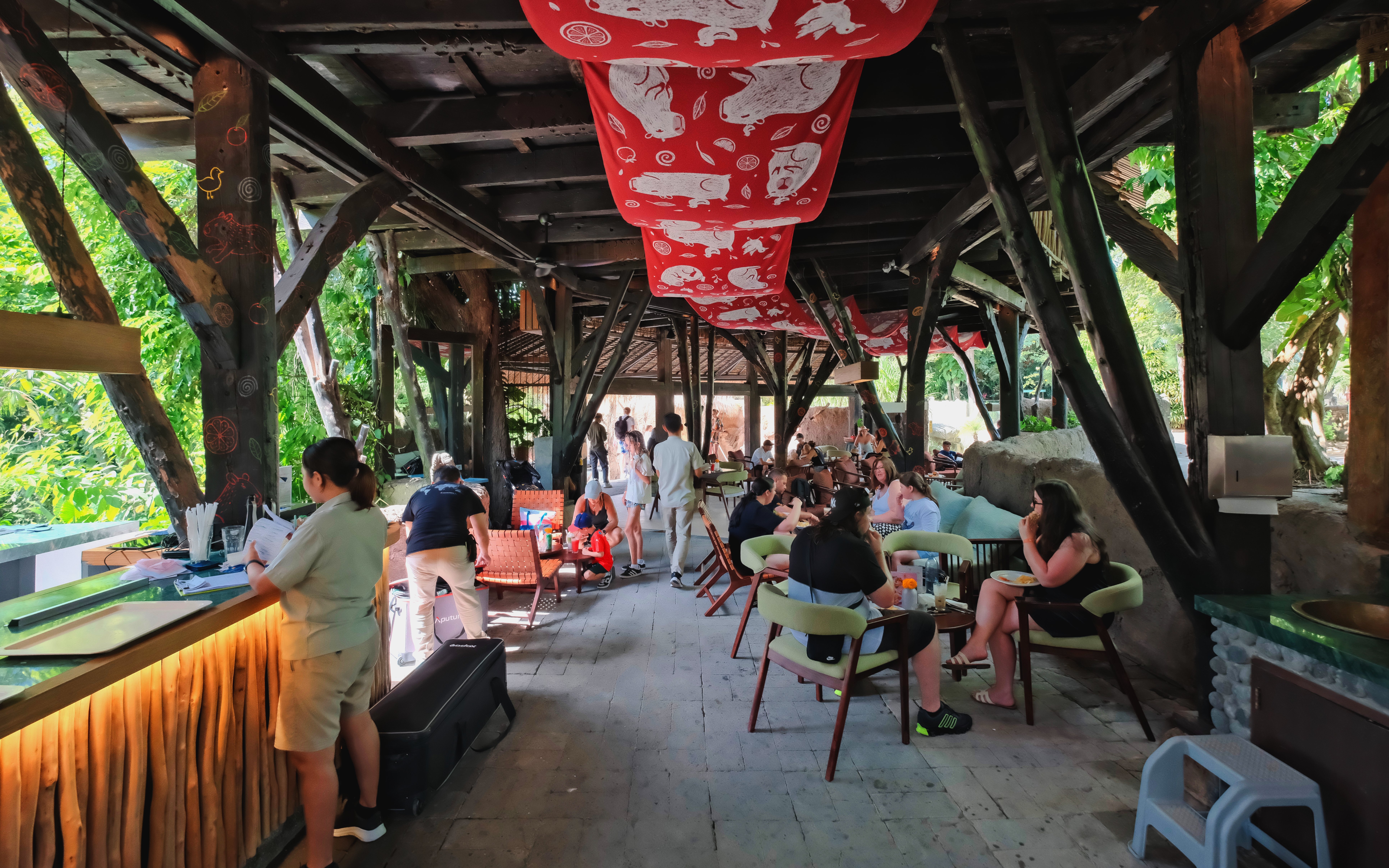 Guests dining in a rustic setting at Bali Zoo, surrounded by lush greenery.