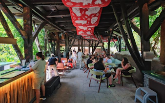 Guests dining in a rustic setting at Bali Zoo, surrounded by lush greenery.