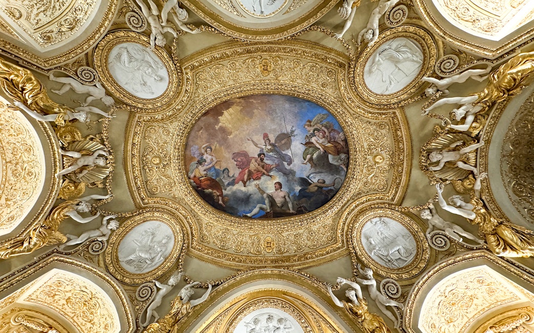 Louvre Museum ceiling artwork with ornate gold details and classical figures.