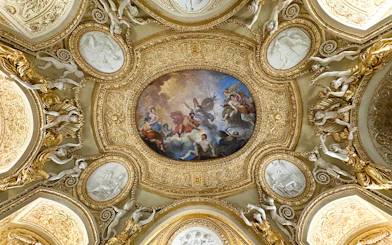 Louvre Museum ceiling artwork with ornate gold details and classical figures.