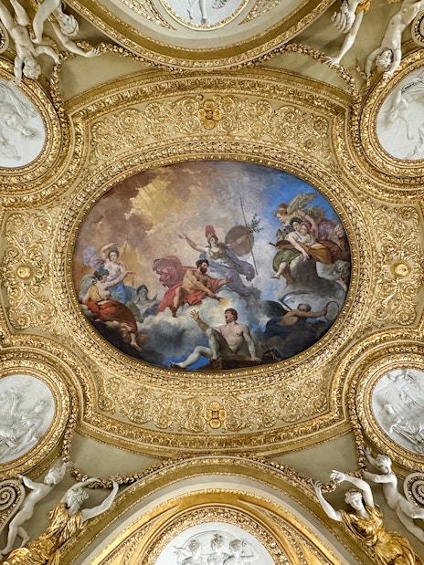 Louvre Museum ceiling artwork with ornate gold details and classical figures.