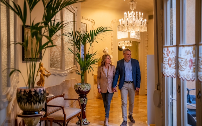 Tourists walking through ornate hallway in Casa Mila, Barcelona.
