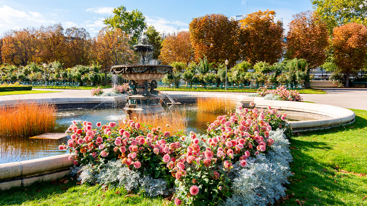 Fountain and flower garden in Vienna near Sisi Museum on a sunny day.