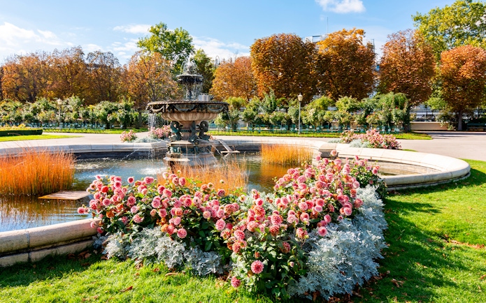 Fountain and flower garden in Vienna near Sisi Museum on a sunny day.