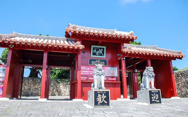 Entrance gate of Murasaki Mura Ryukyu Kingdom Theme Park with traditional Shisa statues.
