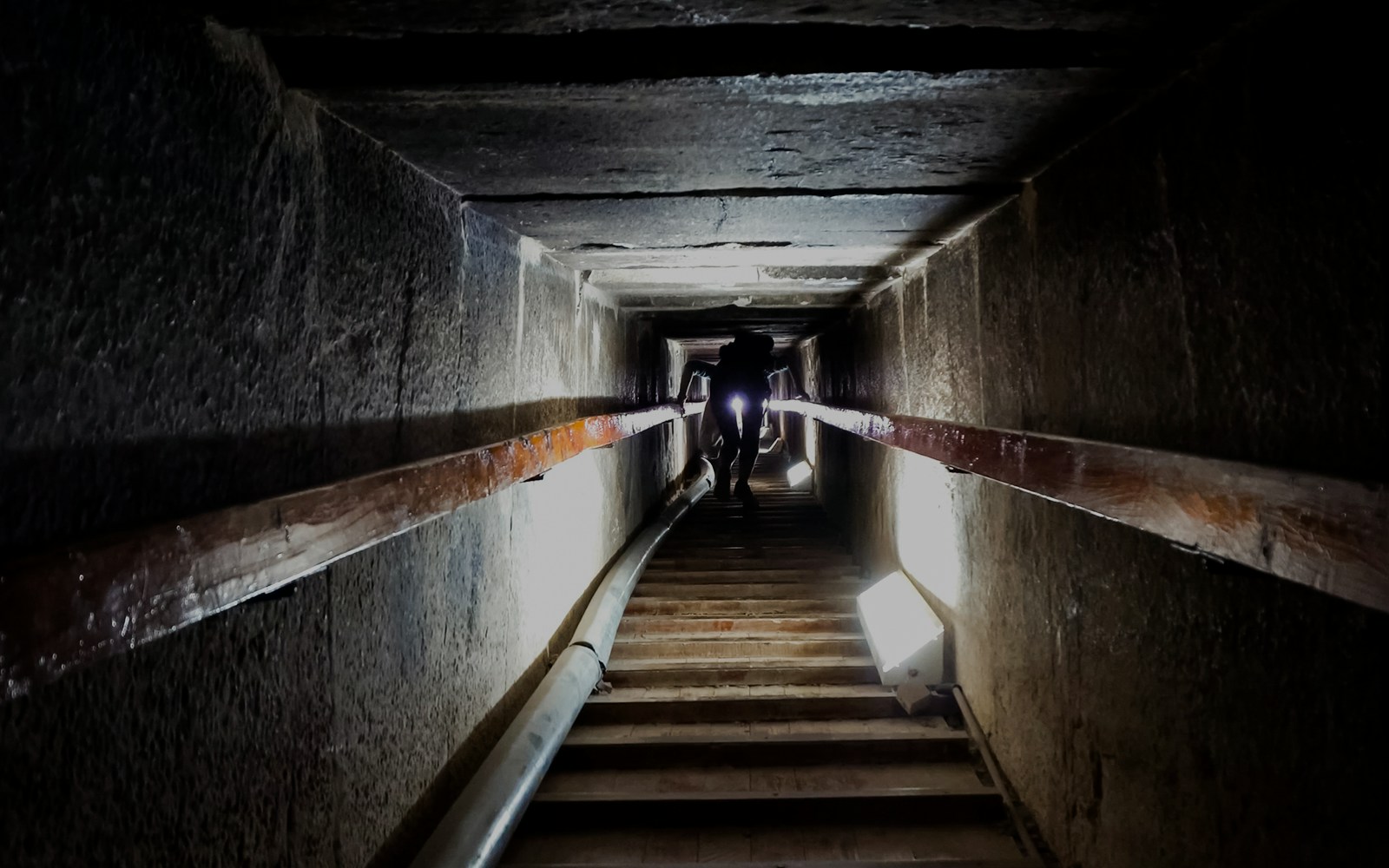 Narrow passageway leading to an ancient burial chamber with a person walking through.