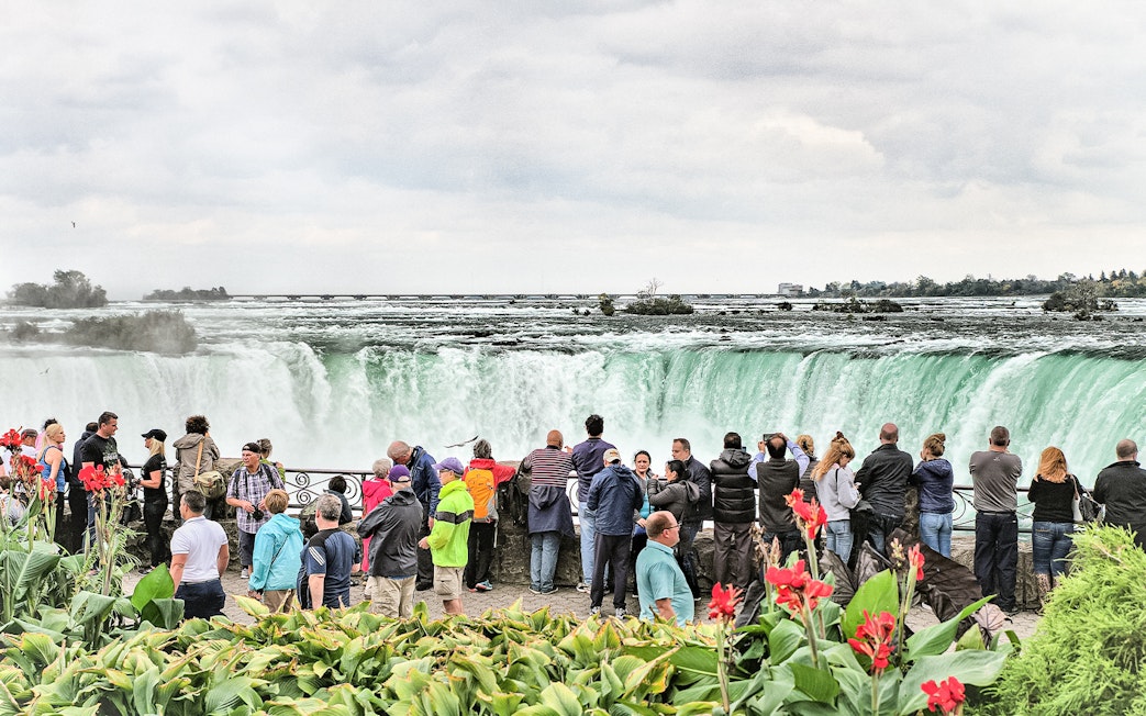 Tourists viewing Niagara Falls from a lookout point in Canada.