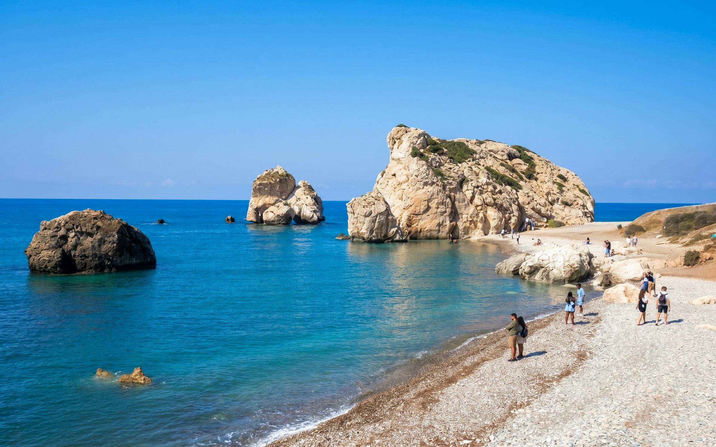 Visitors exploring Aphrodite's Rock on a sunny day in Paphos, Cyprus.