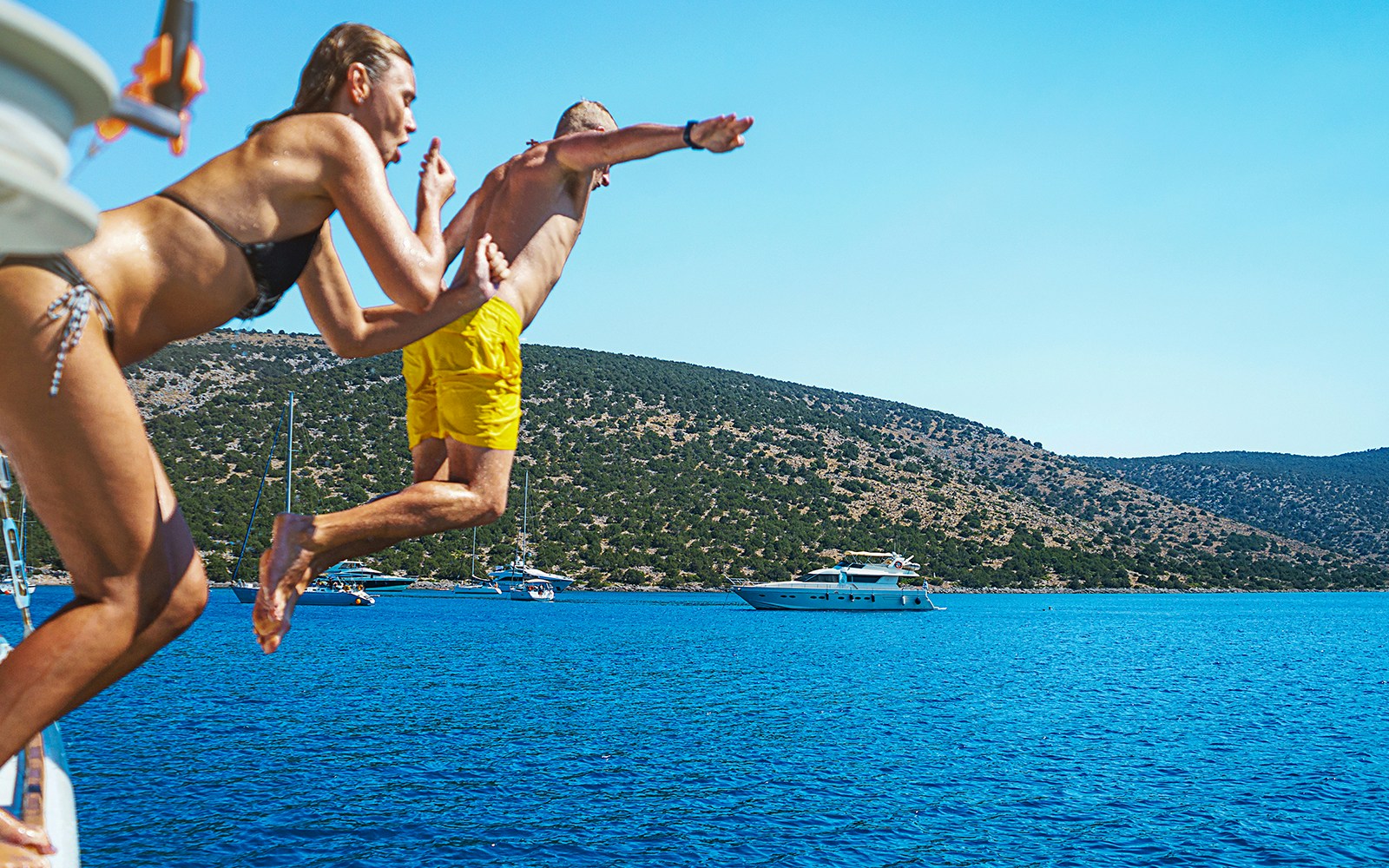 Young couple diving into clear waters near Metopi, part of Athens full-day cruise to Agistri, Moni, and Aegina.