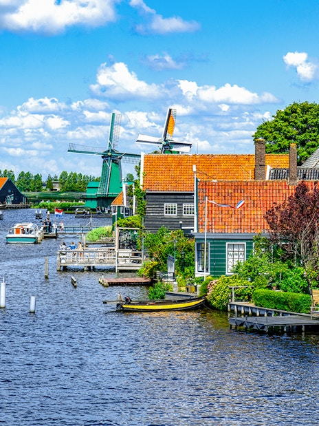 Windmills and traditional houses along the water in Zaanse Schans, Holland.