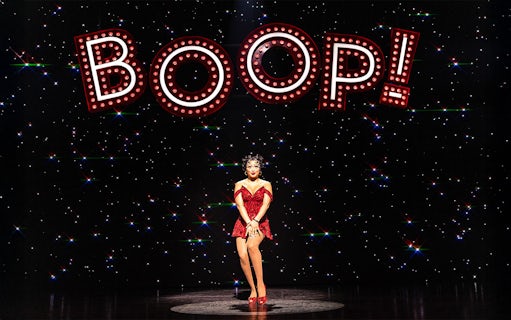 Performer in red dress under "BOOP!" sign in Betty Boop Musical.
