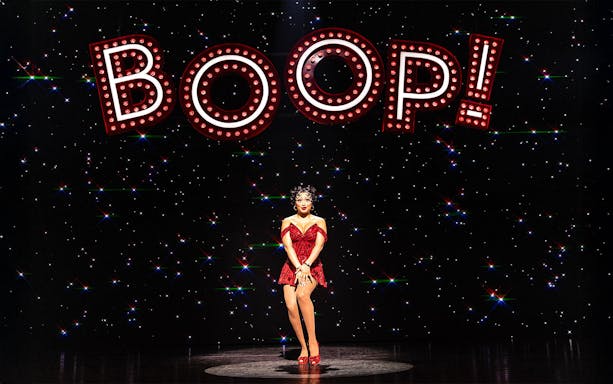 Performer in red dress under "BOOP!" sign in Betty Boop Musical.