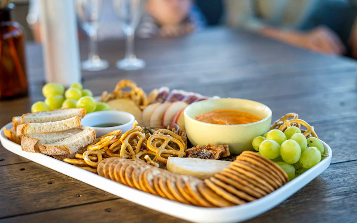 Platter of bread, pretzels, grapes, and dip on a table during Top End Safari Camp tour near Finniss River.