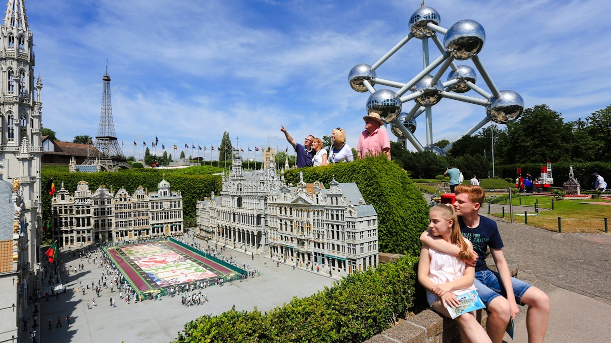 Tourists exploring Mini-Europe park with Atomium in Brussels.