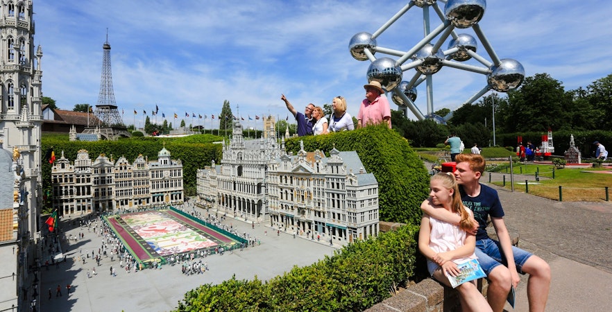 Tourists exploring Mini-Europe park with Atomium in Brussels.