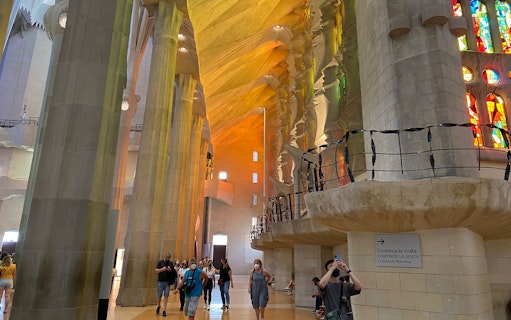 Interior of Sagrada Familia with visitors and colorful stained glass windows, Barcelona.