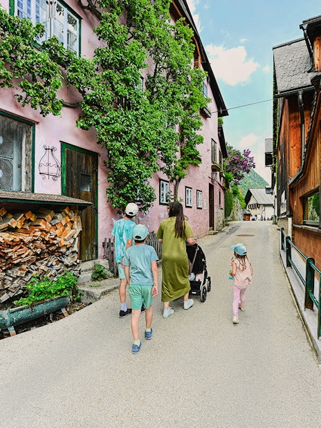 Family walking through a charming street in Hallstatt, Austria, during a day trip from Vienna.