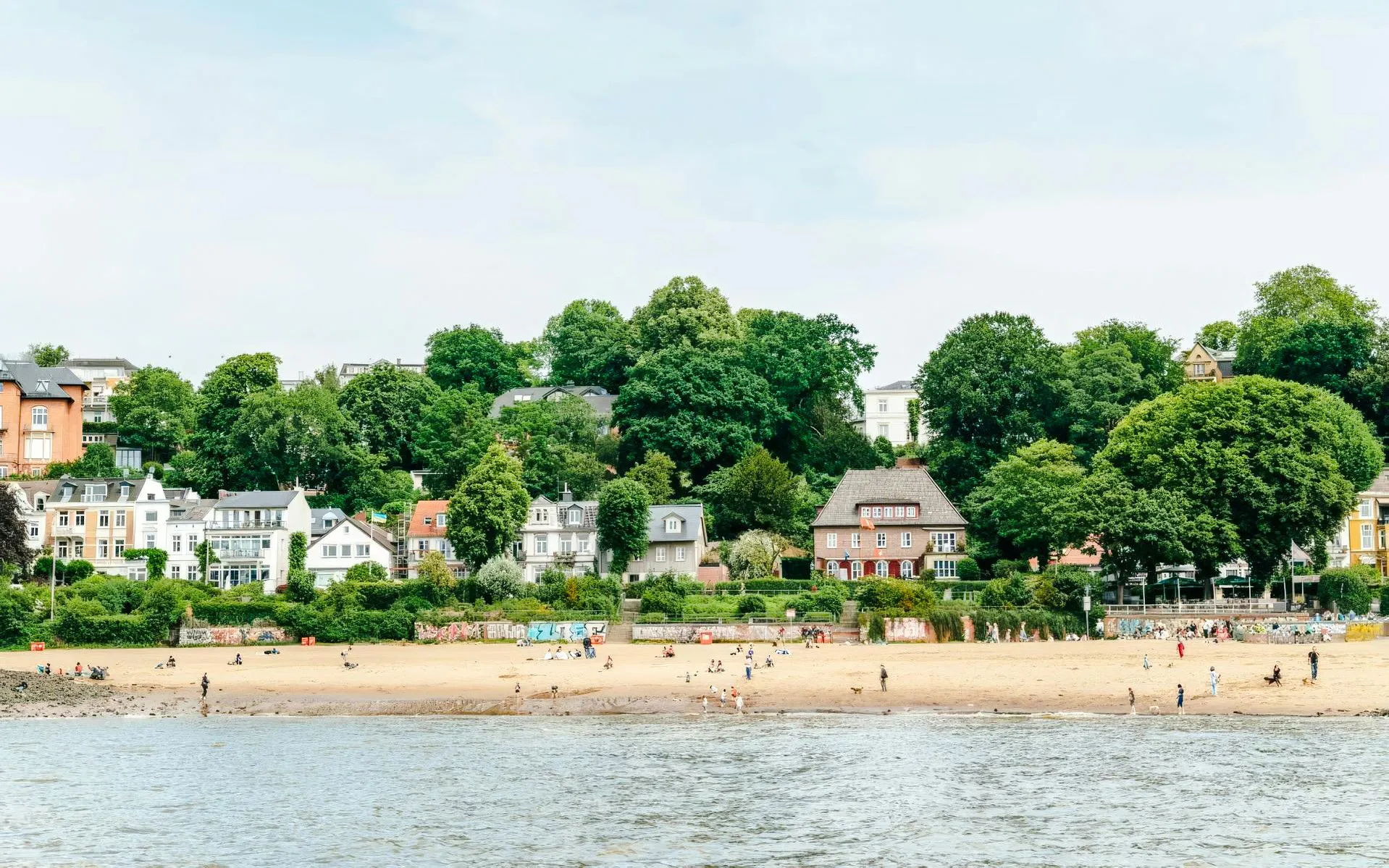Oevelgoenne beach along the Elbe River in Hamburg with people enjoying the sandy shore.