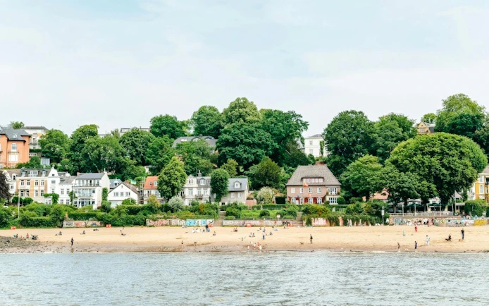 Oevelgoenne beach along the Elbe River in Hamburg with people enjoying the sandy shore.