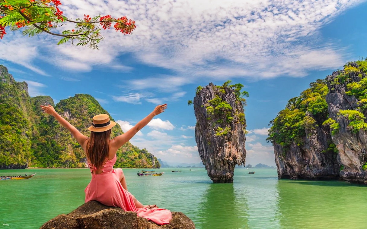 Tourist enjoying view of James Bond Island, Thailand, with limestone cliffs and clear water.