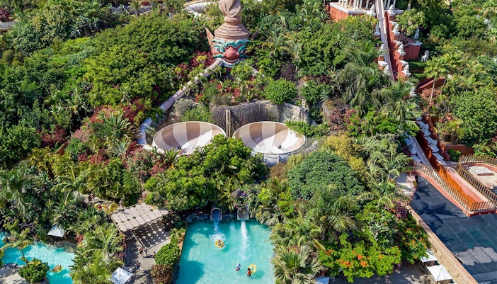 Tourist observing lush tropical greenery and architecture at siam park, Tenerife.