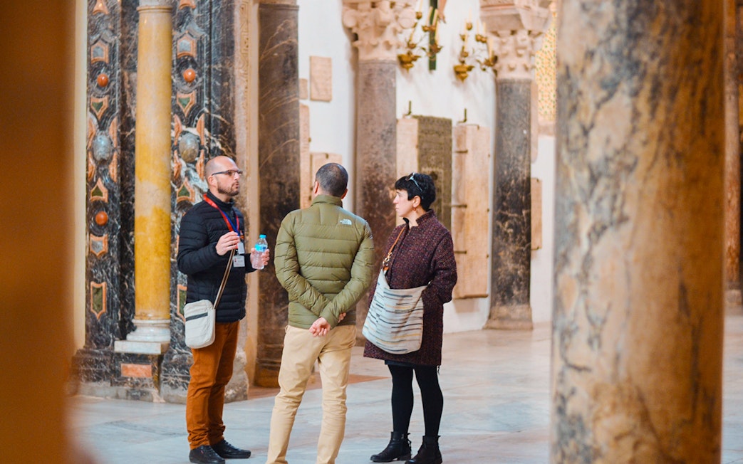Guide explaining history to tourists inside Córdoba Mosque.