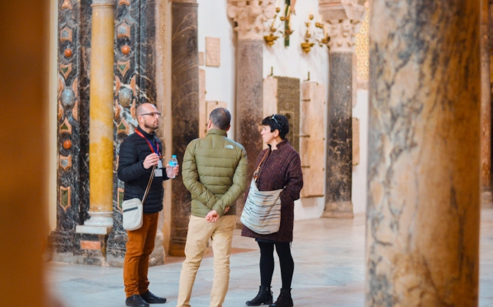 Guide explaining history to tourists inside Córdoba Mosque.