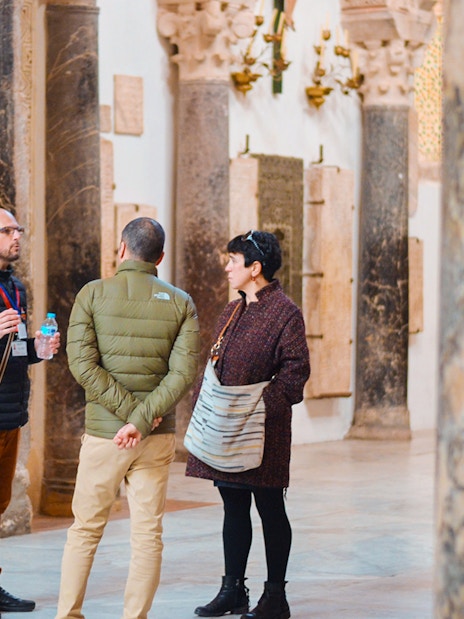 Guide explaining history to tourists inside Córdoba Mosque.