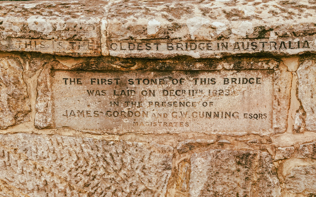 Stone plaque on Australia's oldest bridge, laid in 1823, featured on Port Arthur tour.