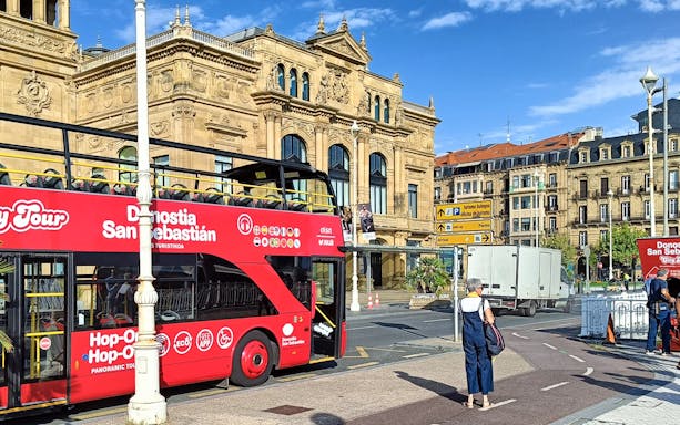 Hop-on hop-off tour bus in front of San Sebastian's historic building.