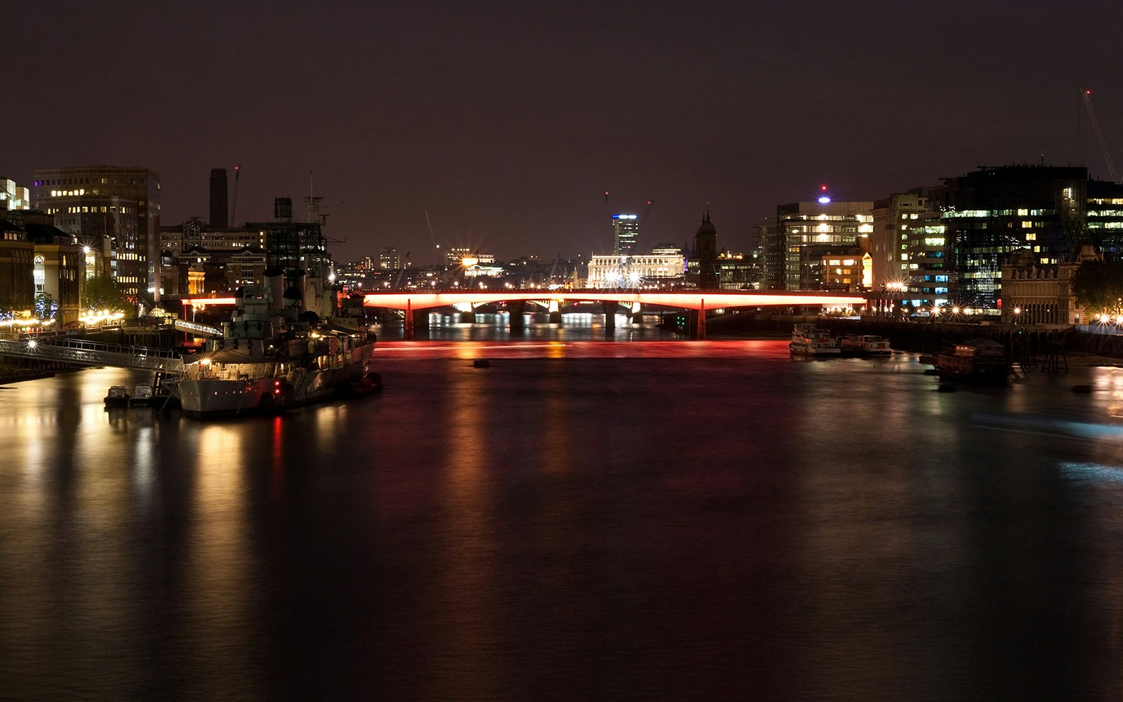 Night view of the illuminated Thames River with a lit-up bridge in London.