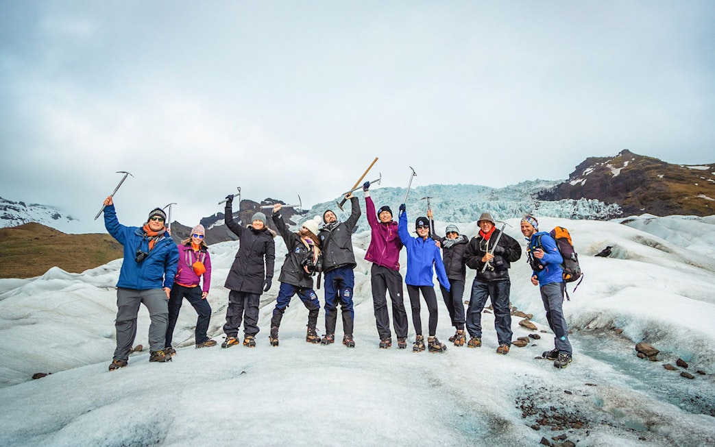 Group of hikers celebrating on Vatnajökull Glacier, Iceland, with ice axes.