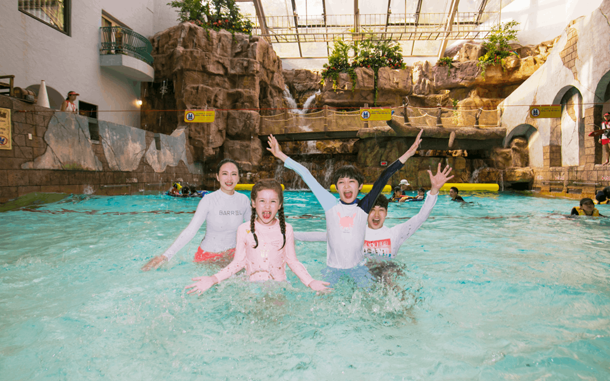 Kids playing in a pool at Caribbean Bay Water Park with waterfalls in the background.