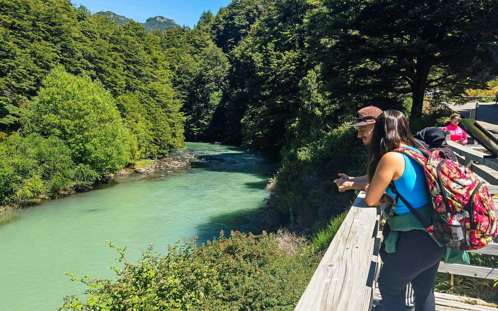 Visitors on a wooden walkway overlooking a river near Los Cántaros Waterfall, Patagonia.