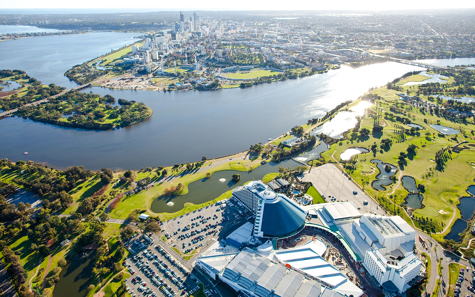 Aerial view of Perth's Optus Stadium and Swan River with city skyline.