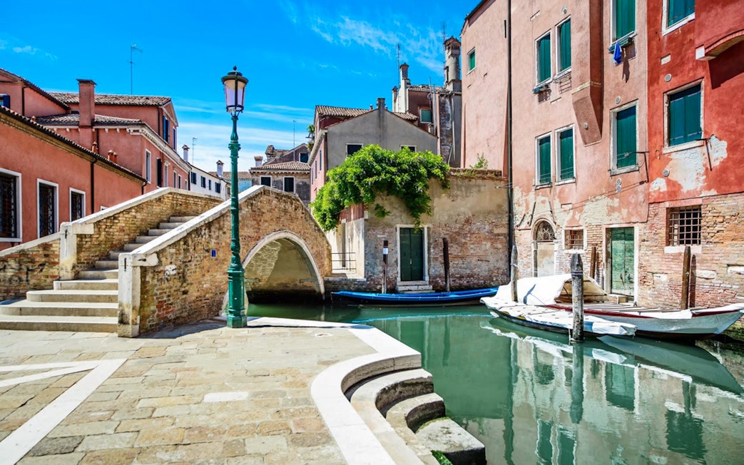 Venice canal with stone bridge and colorful buildings, part of Venice City Pass attractions.