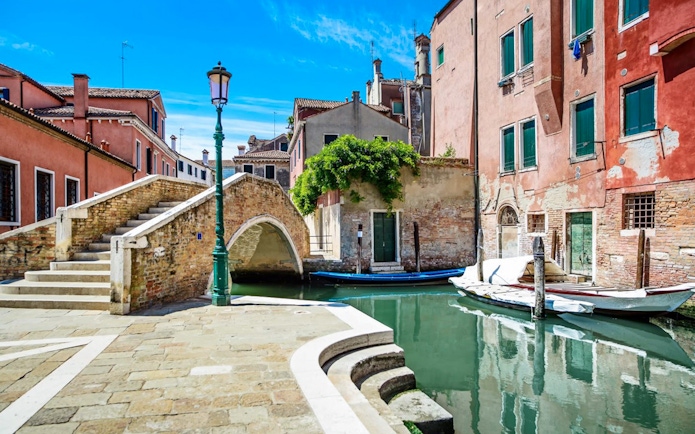 Venice canal with stone bridge and colorful buildings, part of Venice City Pass attractions.
