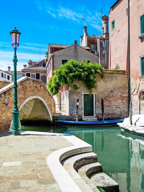 Venice canal with stone bridge and colorful buildings, part of Venice City Pass attractions.
