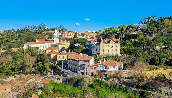 Sintra town road to Quinta da Regaleira, Portugal, surrounded by greenery and historic architecture.