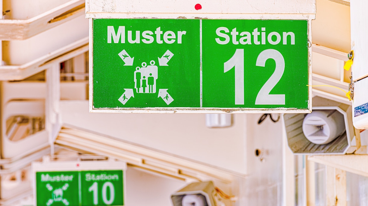 Cruise ship muster point sign indicating safety procedures.