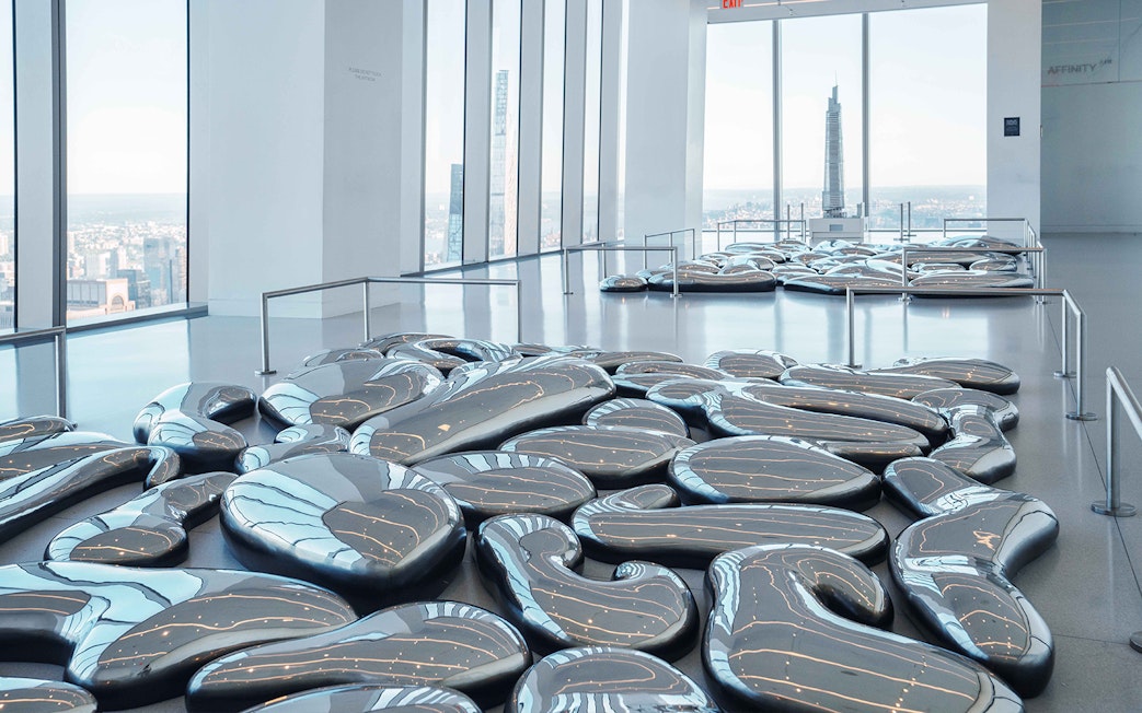SUMMIT One Vanderbilt interior with reflective art installation and city skyline view.