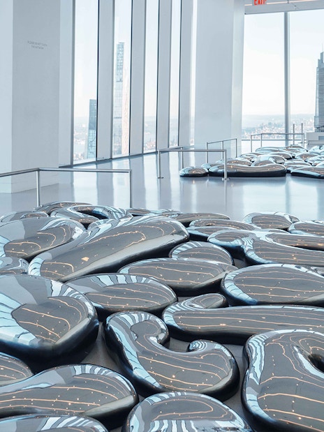SUMMIT One Vanderbilt interior with reflective art installation and city skyline view.