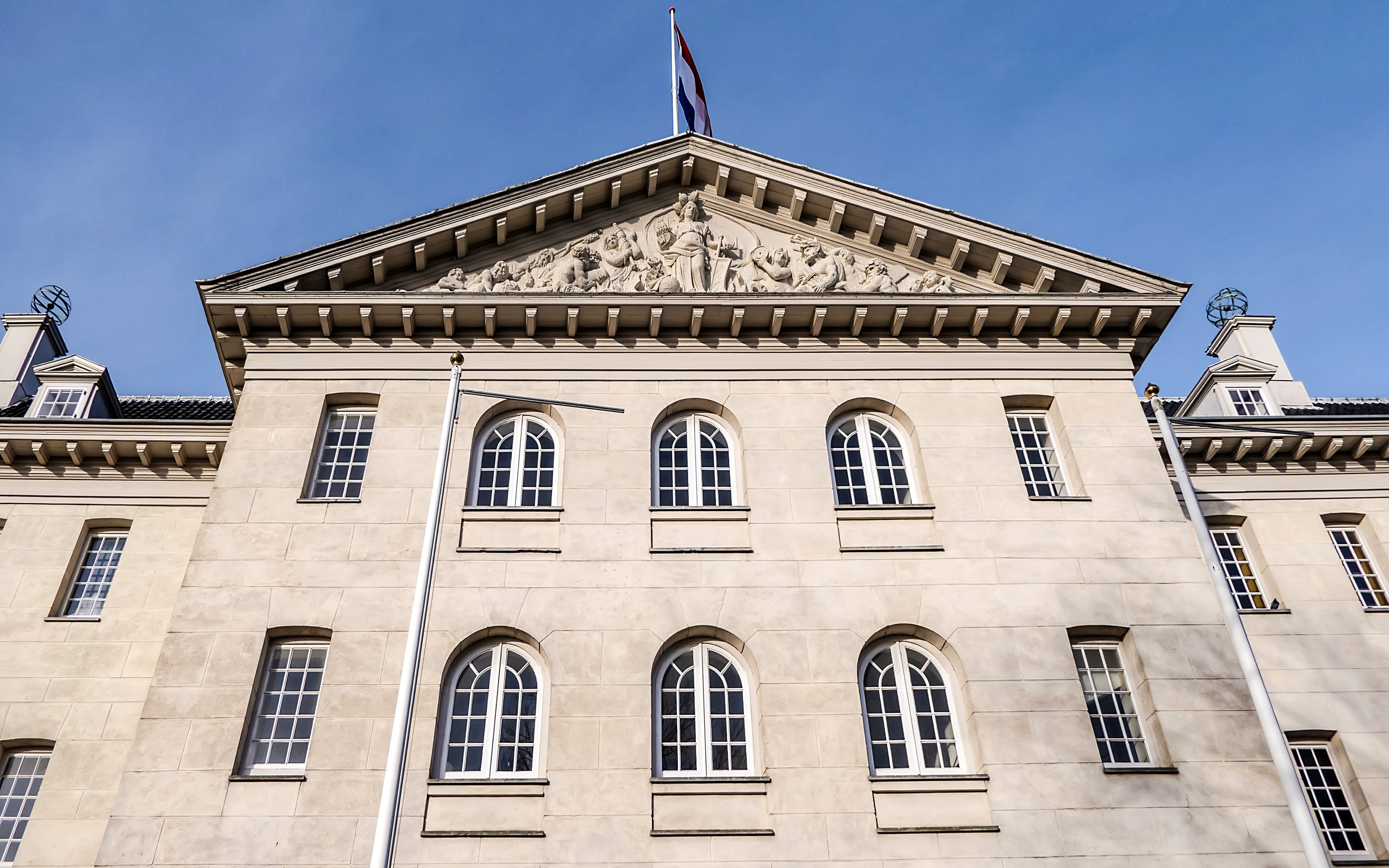 Facade of the National Maritime Museum in Amsterdam with Dutch flag on top.