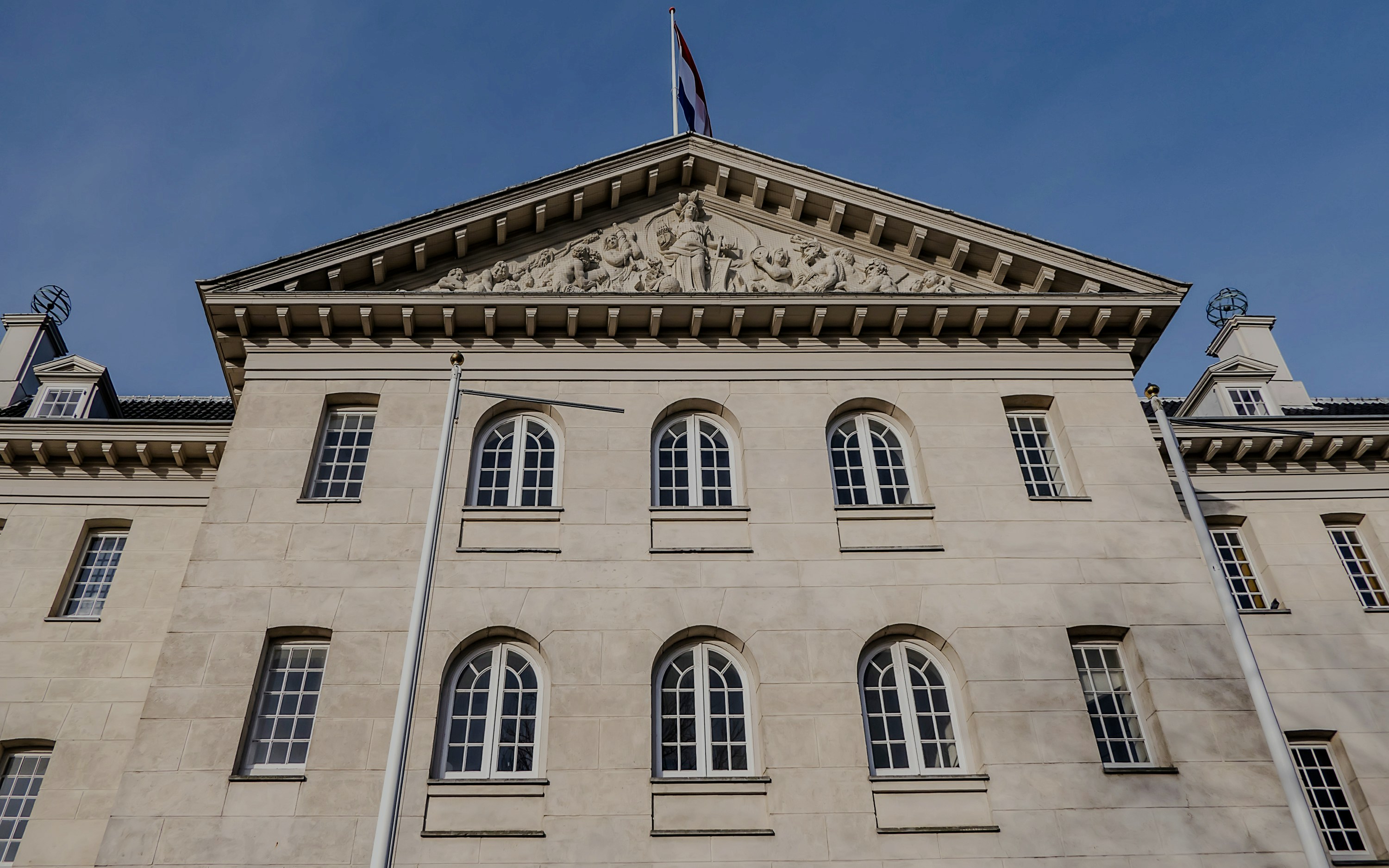 Facade of the National Maritime Museum in Amsterdam with Dutch flag on top.