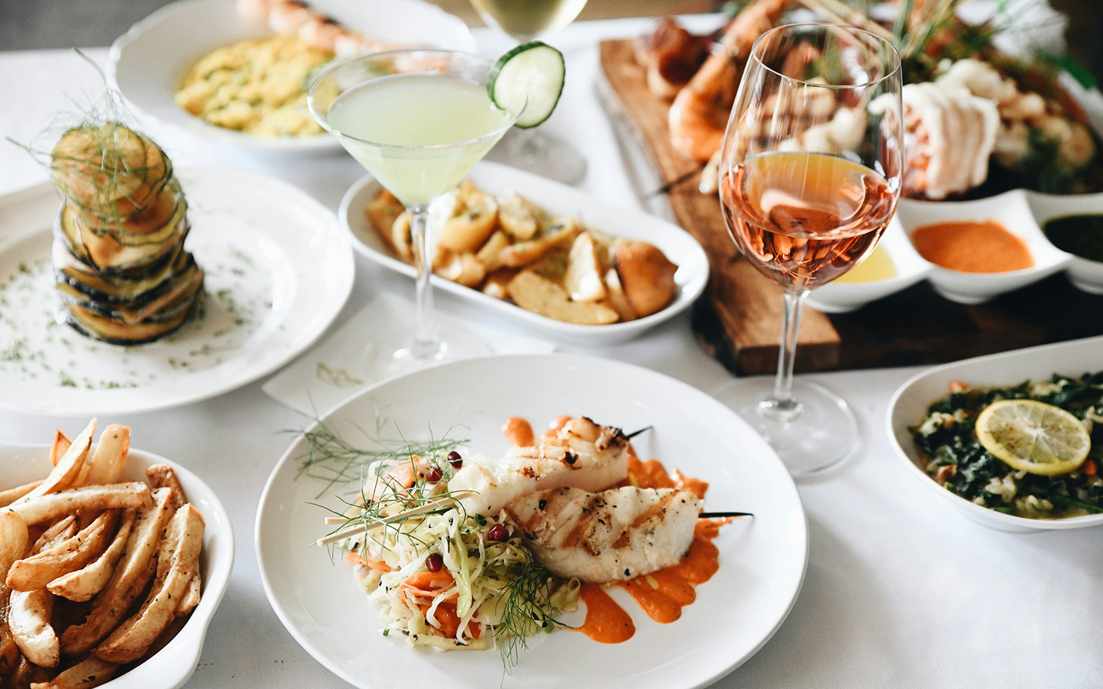 Greek Mediterranean dishes with grilled seafood skewers, roasted vegetables, and cocktails.