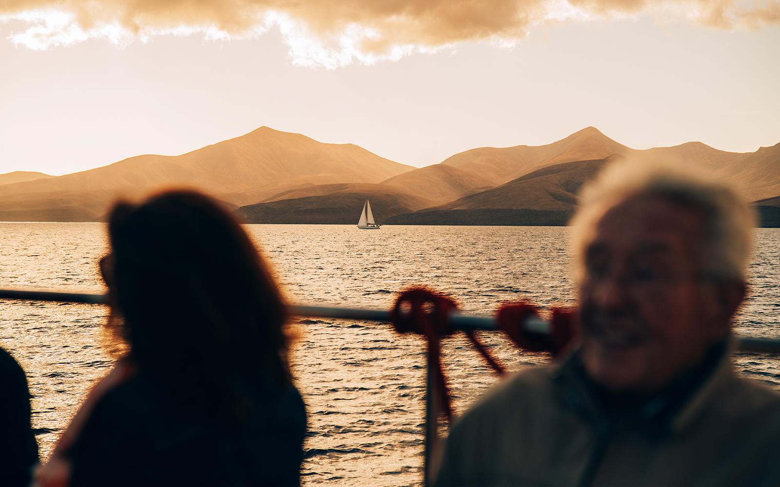 Sailboat on Lanzarote waters at sunset with tourists on deck.