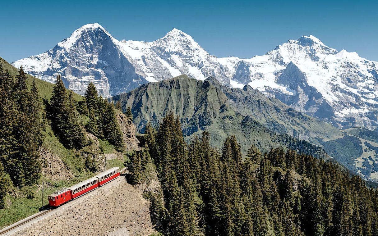 Train ascending Mount Rigi with snow-capped peaks in the background, view from Lucerne day pass.