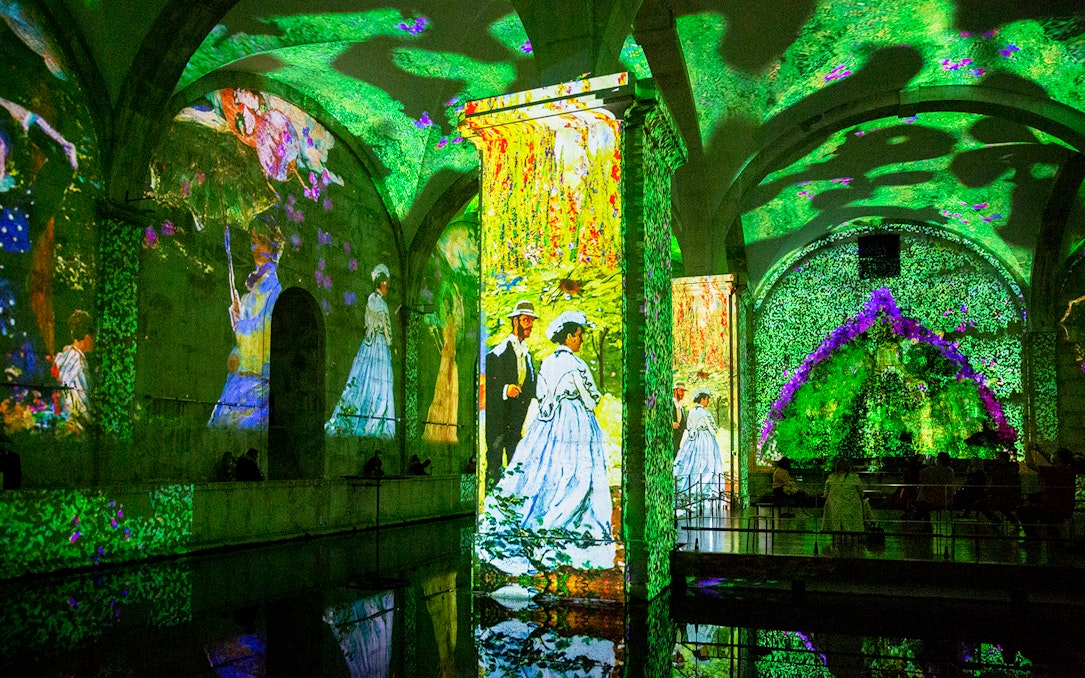 Monet and Klimt artworks projected in immersive exhibition space.